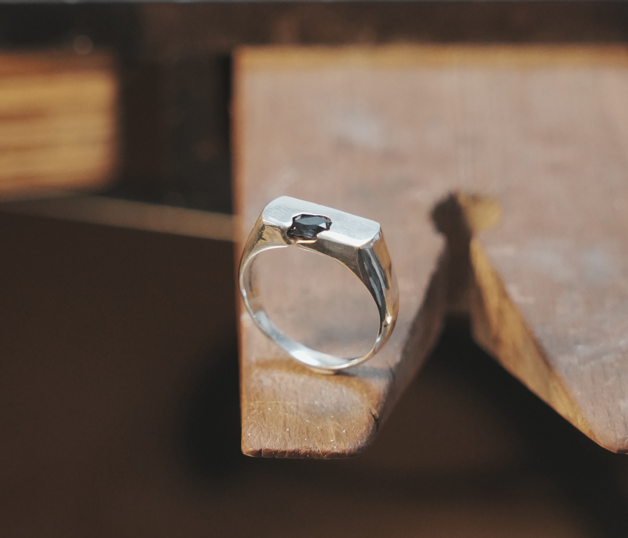 The OIAM No. 1 ring balanced upright on the edge of a wooden block, warm light