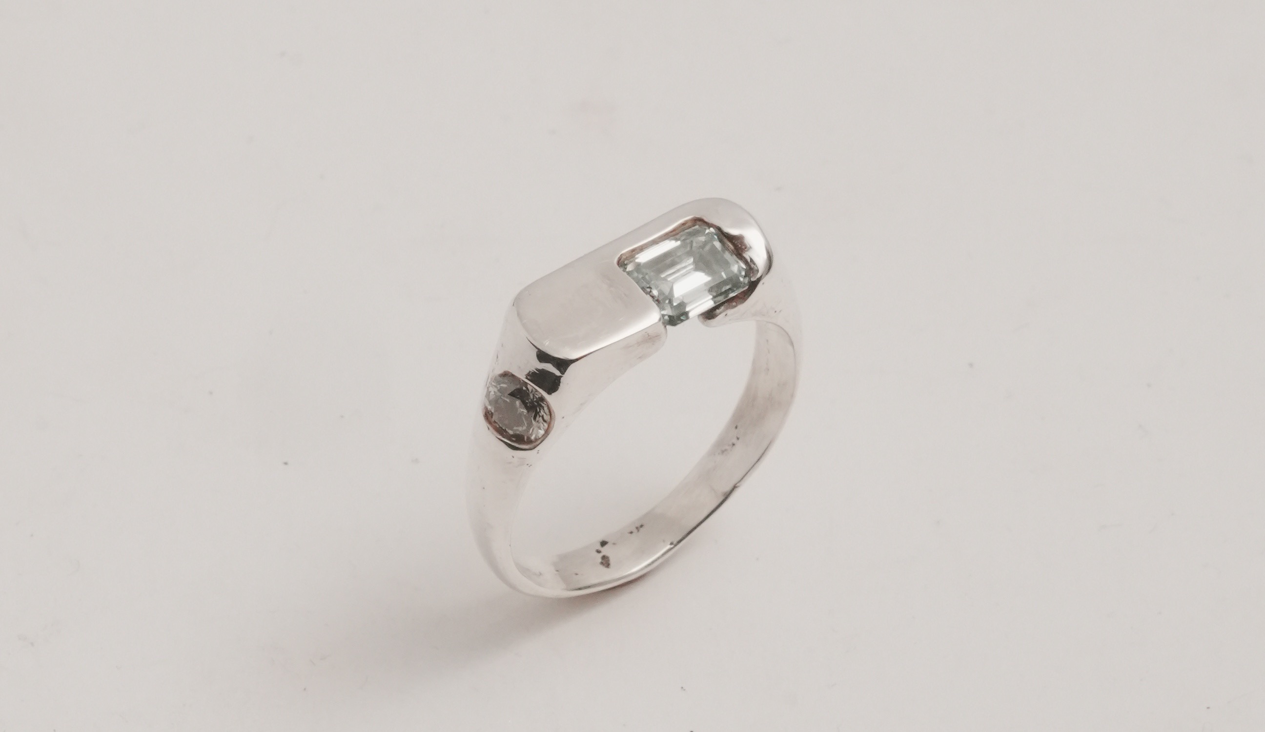 OIAM No. 1. A sterling band set with an emerald-cut blue moissanite and a lab-grown diamond, on a bone backdrop